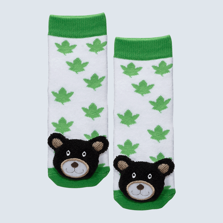 Two socks against a white background. The socks feature white and green maple leaf motifs and a cute plush bear charm on each toe.