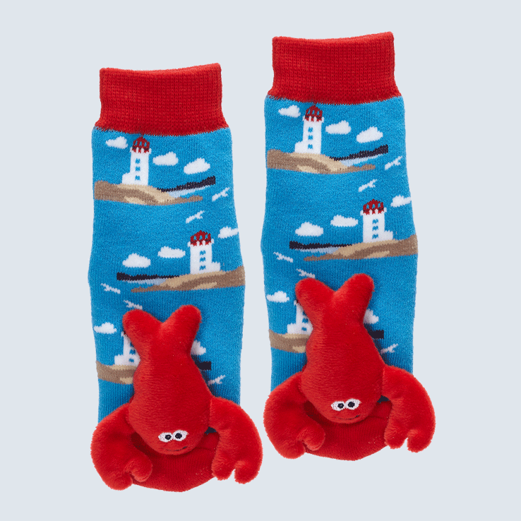 Two socks against a white background. The socks feature a lighthouse motif and a cute plush lobster charm on each toe.