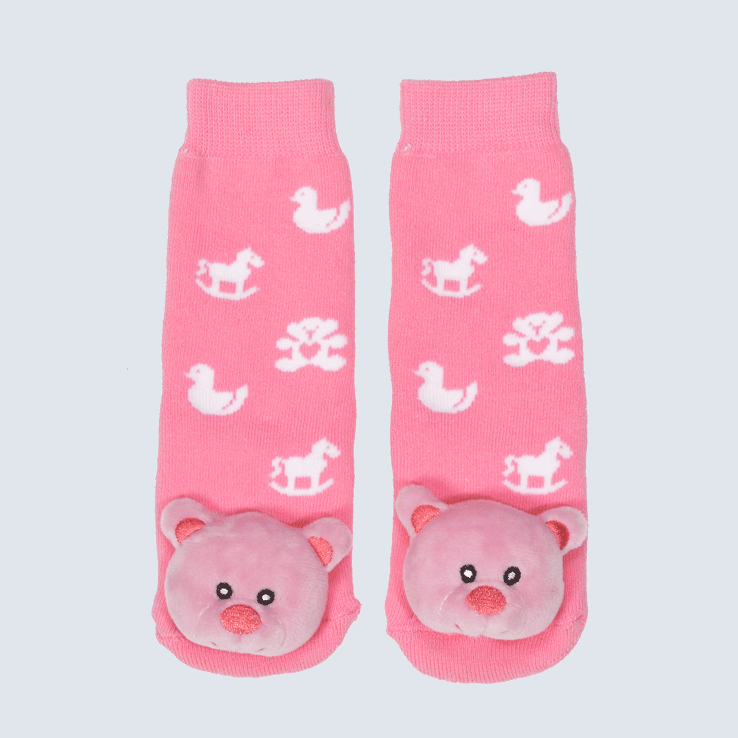 Two pink socks against a white background. The socks feature a toy motifs and a cute plush bear charm on the toe.